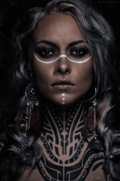 black and white photograph of a woman with tattoos on her body, wearing large hoop earrings