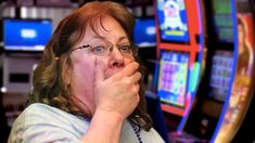 a woman with glasses is eating something in front of slot machines