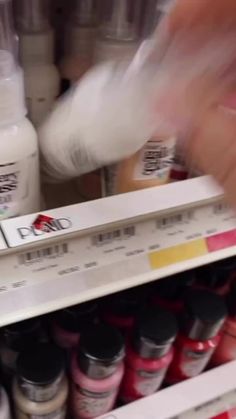 a person is picking up some paint from the shelf in a store or shelving unit