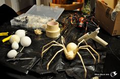 a table topped with fake eggs and plastic spider figures next to construction supplies on top of it