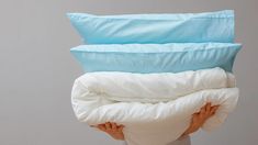 a person holding three pillows on top of each other in front of their face and back