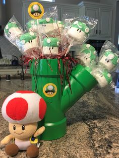 a stuffed toy sitting next to a green vase filled with marshmallows on top of a counter