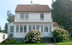 a white house sitting on top of a lush green field