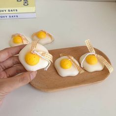 someone is holding up some fake eggs on a wooden tray with ribbon around them and they are ready to eat