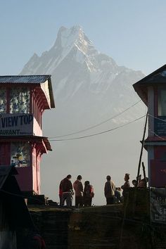 people are standing on the roof of a building with a mountain in the background,