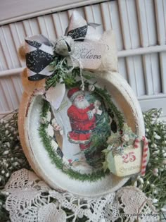 a christmas ornament with a santa clause on it, surrounded by greenery