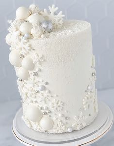 a white frosted cake with snowflakes and ornaments on the top is sitting on a plate