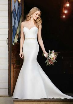 a woman in a white wedding dress is standing on steps and holding a flower bouquet