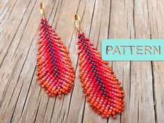 a pair of red and blue beaded earrings sitting on top of a wooden table