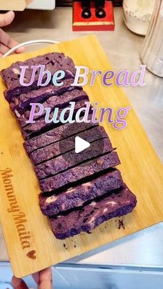 a person holding a cutting board with purple bread on it that says ube bread pudding