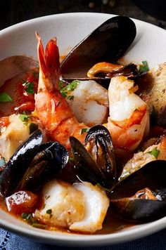 a white bowl filled with seafood and mussels