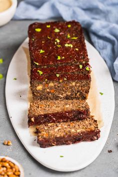 slices of meatloaf sitting on a plate with nuts and sauces around it