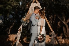 a bride and groom standing in front of a teepee