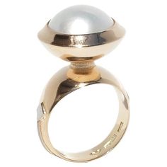 This 18-karat gold and white gold vintage ring features a mabe pearl with a smooth, domed surface, embraced by a bowl-like setting. The ring's shank widens as it approaches the setting, creating an elegant neck with patterned engravings. White gold details in a square shape and a stripe adorn the sides of the shank, accompanied by small engravings near the white gold accents. This ring would be perfect for a stylish garden party or an elegant summer soirée, as its lustrous pearl and intricate go Pearl Cocktail Ring, Gold Pearl Ring, Vintage Cocktail Ring, Estate Rings, Mabe Pearl, Gold Cocktail Ring, Gold Cocktail, Vintage Ring, Topaz Ring