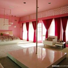 a large bedroom with pink walls and curtains on the window sill, bed in center