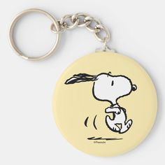 a yellow keychain with a drawing of a snoopy dog holding a ball