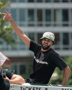 two men sitting on the back of a truck with their hands up in the air