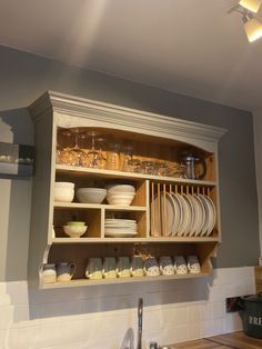 a kitchen cabinet filled with dishes and plates