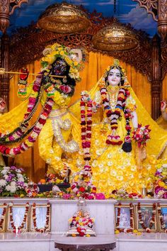 an idol is displayed in front of a stage with flowers on the floor and decorations around it