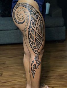 a woman's leg with tattoos on it and a couch in the back ground