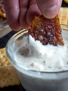 a person dipping something into a small glass bowl