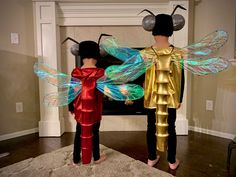 two people dressed up as tinkerbells standing in front of a fire place