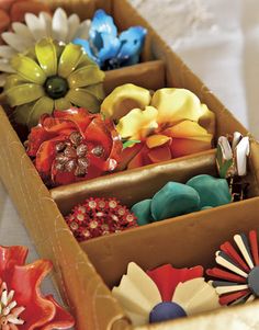 there are many colorful flowers in the box on the table top, and one is made out of cardboard