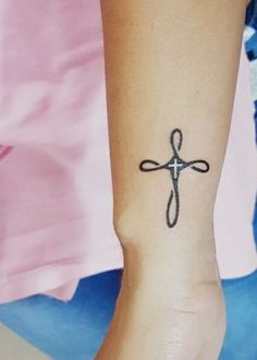 a small tattoo on the wrist of a woman with a cross in it's center