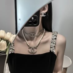 a mannequin wearing pearls and jewelry in front of a mirror with flowers on it