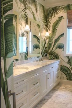 a bathroom with palm leaves on the wall and two sinks in front of it,