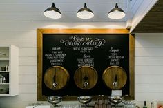 there are three wine barrels on the wall in this kitchen, and one is labeled with different wines