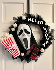 a wreath with a ghost face, popcorn and a cell phone hanging on the front door