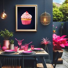 a table with pink plates and cups on it in front of a framed cupcake