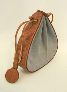 a small purse with a wooden handle on a white surface, it has a leather tag hanging from the strap