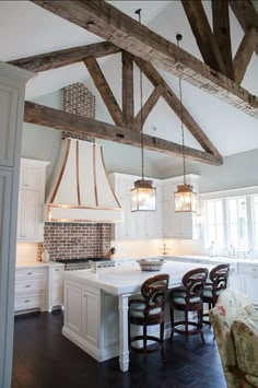 a kitchen with white cabinets and an island in the middle, surrounded by wooden beams