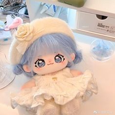 a doll with blue hair and big eyes sitting on a counter next to other items