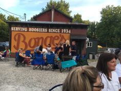 people sitting in lawn chairs near a sign that reads serving hosiers since 1934