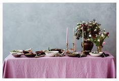 a table topped with lots of plates and bowls next to a vase filled with flowers