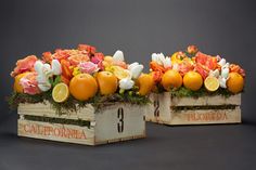 two wooden boxes filled with oranges and flowers