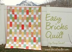 a quilt hanging on a fence next to a sign that says easy brickes quilt