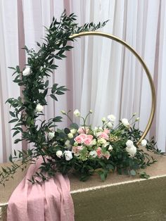 an arrangement of flowers on a table with a pink blanket and white curtains in the background