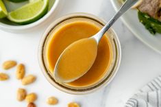 a spoon in a jar filled with peanut butter and topped with lime wedges on the side