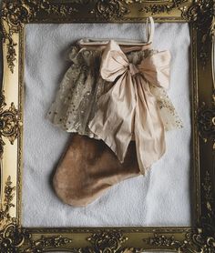 a christmas stocking hanging in a gold frame with a bow on it's head