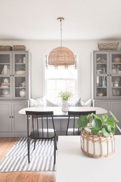 a dining room table with chairs and a potted plant in front of the window