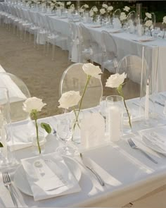 the table is set with white linens and flowers in vases, silverware, and napkins