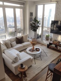 a living room filled with furniture and large windows overlooking the cityscape in the distance