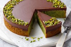 there is a chocolate cake with pistachios on the top and one slice missing