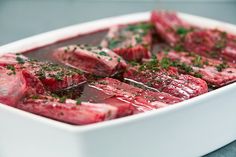 raw meat in a white dish with herbs on top