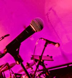 a microphone and drums in front of a purple background