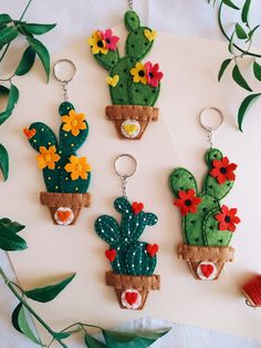 three felt cactus keychains with flowers on them